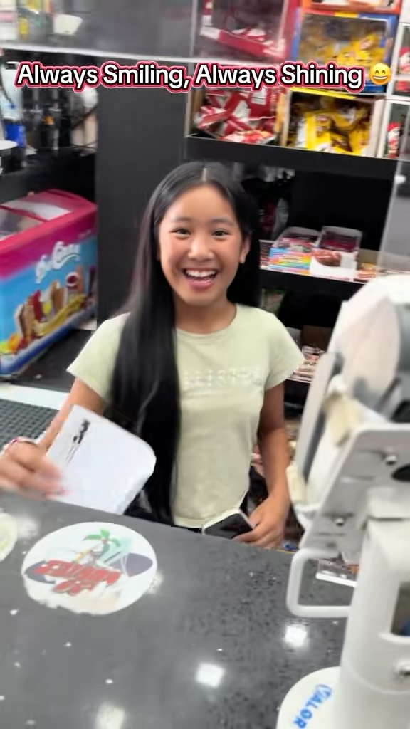 A smiling student holding a school paper at a deli counter.