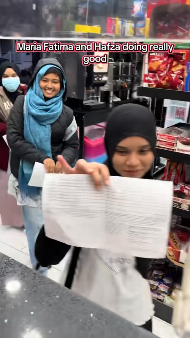 Two students presenting school papers at a deli counter.